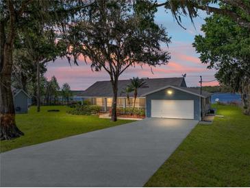 Charming single-story home with a well-manicured lawn and beautiful water view at sunset at 18253 Townsend House Rd, Dade City, FL 33523