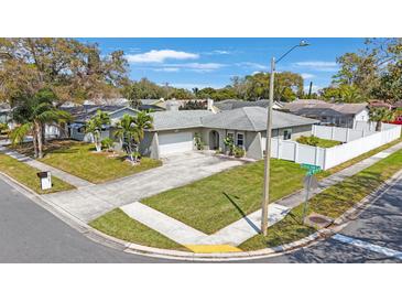 Charming single-story home featuring a well-manicured lawn and a white picket fence enhancing curb appeal at 1947 Citrus Hill Ln, Palm Harbor, FL 34683