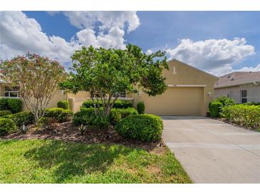 Well-maintained single-story home with lush landscaping, a manicured lawn, and a spacious two-car garage at 2286 Sifield Greens Way # 2286, Sun City Center, FL 33573