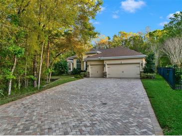 Beautiful single-story home boasting a three-car garage and a long brick paver driveway at 3198 Thatcher Ln, Tarpon Springs, FL 34688