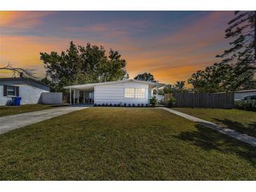 Charming single-story home with a well-manicured lawn and quaint carport against a colorful evening sky at 4030 Marlin Se Dr, St Petersburg, FL 33705