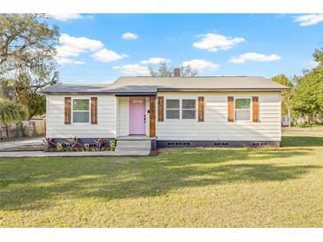 Charming single-story home with a well-manicured lawn, decorative shutters, and a cheerful pink front door at 501 W Bird St, Tampa, FL 33604