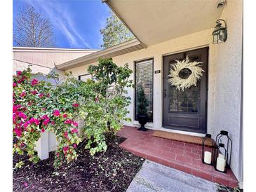 Charming front entrance with brick landing, a decorative wreath, and beautiful bougainvillea at 610 S Woodlands Dr, Oldsmar, FL 34677
