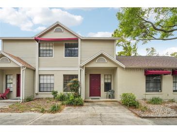 Charming townhome with a red front door, awning, and well-maintained landscaping at 8419 Laurelon Pl, Temple Terrace, FL 33637