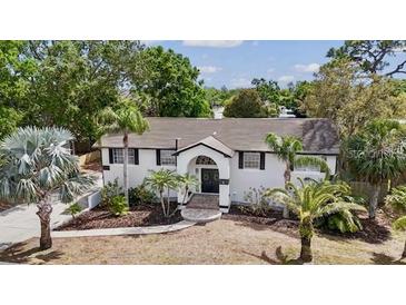 Charming single-story home with a well-manicured lawn, palm trees, and a welcoming front entrance at 1037 Jamaica Way, Tarpon Springs, FL 34689