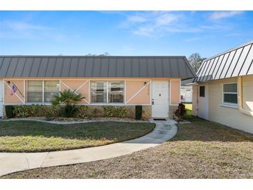 Charming single-story home featuring a metal roof, manicured lawn, and inviting walkway at 11719 Boynton Lane, New Port Richey, FL 34654