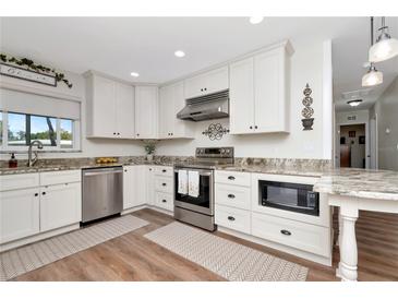 Bright kitchen features white cabinets, granite countertops, stainless steel appliances, and hardwood floors at 13596 Croft N Dr, Largo, FL 33774