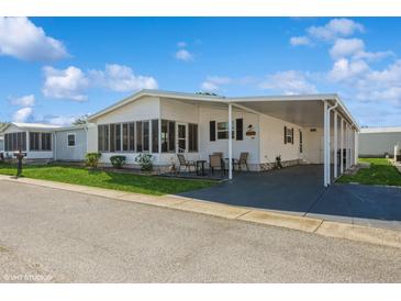 Charming single-story home with carport, screened porch, and well-maintained landscaping under a bright blue sky at 443 Tuna Ct, Oldsmar, FL 34677