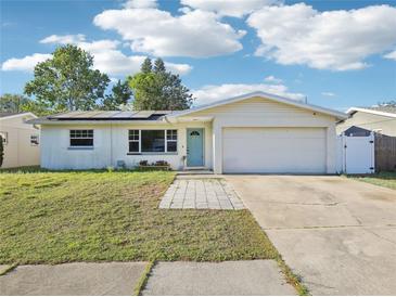 Charming single-story home with a well-manicured lawn, a two-car garage, and solar panels on the roof at 8386 78Th Ter, Seminole, FL 33777