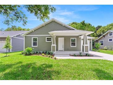 Charming home with a covered front porch, green siding, and landscaped front yard at 9303 N 19Th St, Tampa, FL 33612