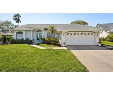 Charming one-story home with lush lawn, mature landscaping and a driveway leading to an attached two-car garage at 13553 Landers Dr, Hudson, FL 34667