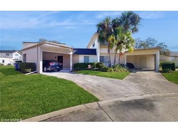 Charming home featuring a spacious driveway, carport, and lush landscaping with mature palm trees at 2572 Forest Run Ct, Clearwater, FL 33761