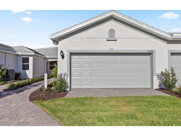 A well-maintained two-car garage with a gray door, set amidst a lush green lawn at 25969 Bimini Sands Ct, Englewood, FL 34223