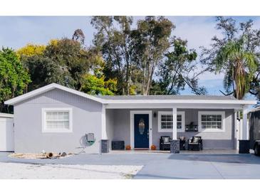 Charming single-story home with blue front door, manicured lawn and welcoming front porch with chairs at 314 E Althea Ave, Tampa, FL 33612