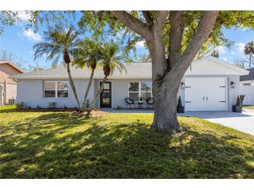 Charming single-story home featuring well-manicured lawn, fresh gray paint, and mature landscaping at 3352 Honeymoon Ln, Holiday, FL 34691