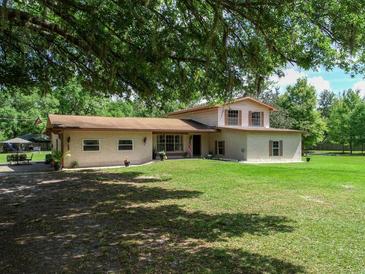 Charming two-story home with a well-maintained lawn and mature trees providing shade at 4902 Five Acre Rd, Plant City, FL 33565