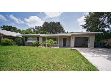 Charming single-story home with an attached garage and a well-manicured front yard at 1619 San Roy Dr, Dunedin, FL 34698