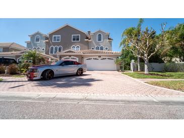 Charming two-story townhome with a well-manicured lawn and a spacious two-car garage and red paved driveway at 1806 Lago Vista Blvd, Palm Harbor, FL 34685