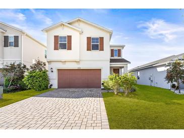 Charming two-story home showcasing a manicured lawn, paver driveway, and a neutral color scheme at 34024 White Fountain Ct, Wesley Chapel, FL 33545