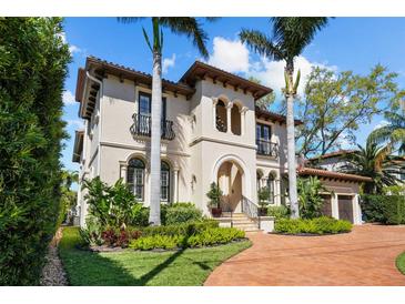 Stunning two-story Mediterranean home featuring lush landscaping and a red brick driveway leading to an arched entryway at 44 Martinique Ave, Tampa, FL 33606