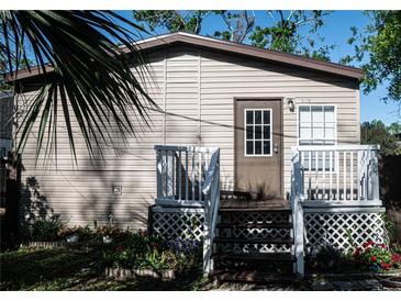 Charming home featuring a front porch with white railings, a brown door, and light beige siding at 12720 Four Oaks Rd, Tampa, FL 33624