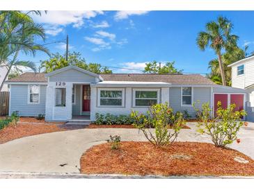Charming single-story home featuring a well-manicured front yard, light gray exterior, and brick accents around the entry at 129 94Th Ave, Treasure Island, FL 33706