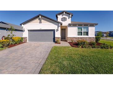 Charming single-Gathering home features a well-manicured lawn and a gray brick driveway leading to an attached two-car garage at 34329 Evergreen Hill Ct, Wesley Chapel, FL 33545