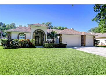 Charming home featuring a manicured lawn, brick accents, arched doorway and a three car garage at 2749 Bent Leaf Dr, Valrico, FL 33594
