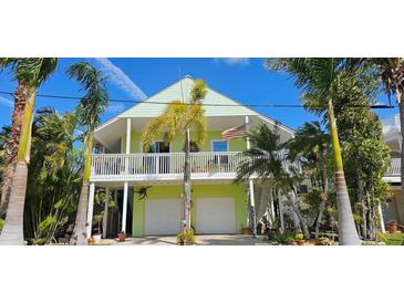 Charming coastal home featuring a covered balcony, two-car garage, and lush tropical landscaping at 112 13Th Ave, Indian Rocks Beach, FL 33785