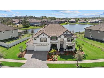 Beautiful home with three-car garage, tiled roof, and landscaping, situated near a serene lake at 33105 Kateland Dr, Wesley Chapel, FL 33545