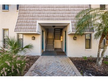 Charming building entrance featuring a brick walkway, tropical landscaping, and an inviting entryway at 720 Lyndhurst St # 1121, Dunedin, FL 34698