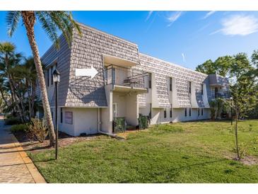 Charming condo exterior with a balcony, lush lawn, and mature trees on a sunny day at 720 Lyndhurst St # 1121, Dunedin, FL 34698