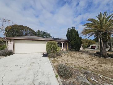 Charming single-story home featuring a two-car garage and partially xeriscaped front yard at 7735 Gaston Dr, Port Richey, FL 34668