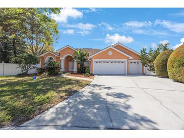 Charming single-story home boasts a three-car garage and manicured landscaping in a suburban neighborhood at 2302 Azalea Dr, Palm Harbor, FL 34683