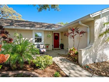 Inviting front entrance with a red door and well-maintained landscaping for a welcoming curb appeal at 304 Jean St, Palm Harbor, FL 34683