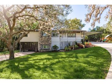 Charming two-story home featuring a stone facade, carport, landscaped front yard, and mature trees at 317 Old East Lake Rd, Tarpon Springs, FL 34688
