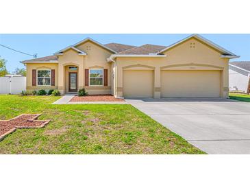Charming, single-story home featuring stucco siding, a manicured lawn, and a two-car garage at 12442 Curry Dr, Spring Hill, FL 34609