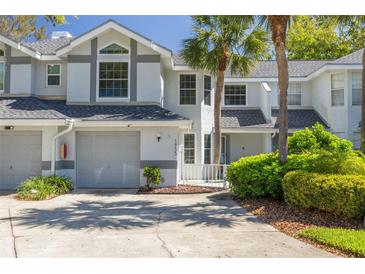 Charming two-story townhouse with attached garage, mature trees, and landscaped front yard offering curb appeal at 1955 Georgia N Cir, Clearwater, FL 33760