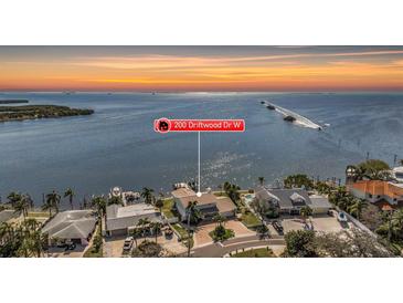 Stunning aerial view of waterfront home showcasing beautiful landscaping, a private dock, and serene water views at 200 Driftwood W Dr, Palm Harbor, FL 34683