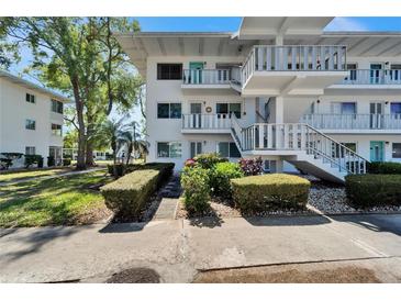 White condo building featuring well-maintained landscaping and inviting staircases at 8454 111Th St # 201, Seminole, FL 33772