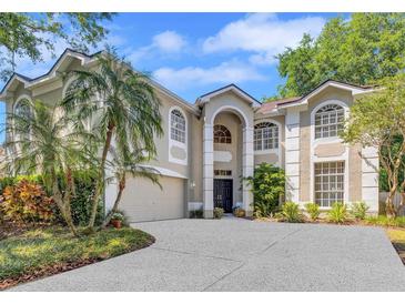 Elegant two-story home with stucco exterior, arched windows, lush landscaping, and a concrete driveway leading to an attached garage at 9314 Heritage Oak Ct, Tampa, FL 33647