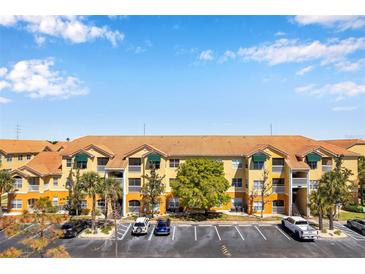 Spacious yellow apartment building with tile roof, manicured landscaping, and ample parking on a sunny day at 10764 70Th Ave # 6105, Seminole, FL 33772