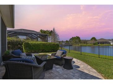 Relaxing patio with waterfront view, outdoor seating, and screened-in lanai beyond at 14885 Caravan Ave, Odessa, FL 33556