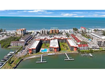 Stunning aerial view of a coastal condo complex with a pool, boat docks, and ocean access at 19701 Gulf Blvd # 231, Indian Shores, FL 33785