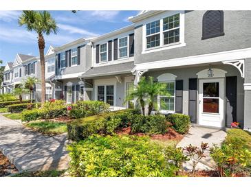 Charming townhome with gray stucco, black shutters, and professionally landscaped front yard at 297 Countryside Key Blvd, Oldsmar, FL 34677