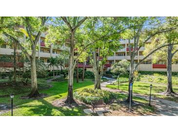 Exterior view of building with lush landscaping, mature trees, and pathways at 3076 Eastland Blvd # 305, Clearwater, FL 33761