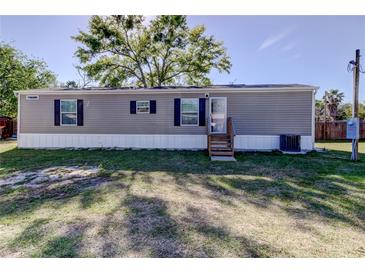 Well-maintained home with gray siding, complemented by black shutters and a manicured lawn, and mature trees at 9420 Kiowa Dr, New Port Richey, FL 34654