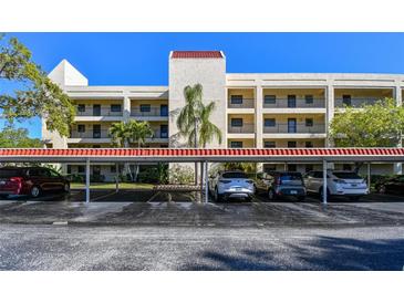 Exterior view of the four-story condo building with covered parking and well-maintained landscaping at 11485 Oakhurst Rd # A202, Largo, FL 33774