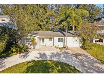 Inviting single-story home showcases a freshly graveled driveway, manicured lawn, and cozy seating area at 1908 Sutherland W Dr, Palm Harbor, FL 34683