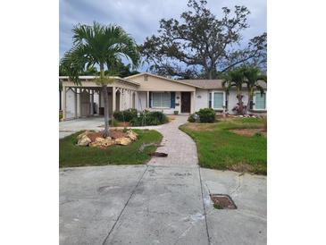 Charming single-story home with carport, landscaped yard, and brick walkway at 201 S Treasure E Dr, Tampa, FL 33609